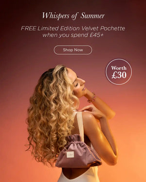 Woman holding limited edition pochette with against sunset background - Spend £45 receive a free Velvet Pochette